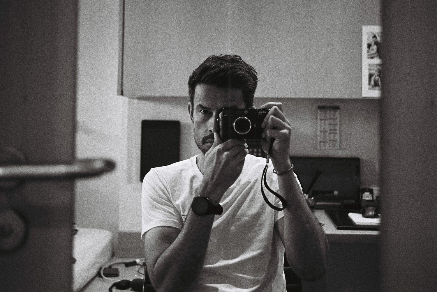 Black and white mirror portrait of Charl holding a camera